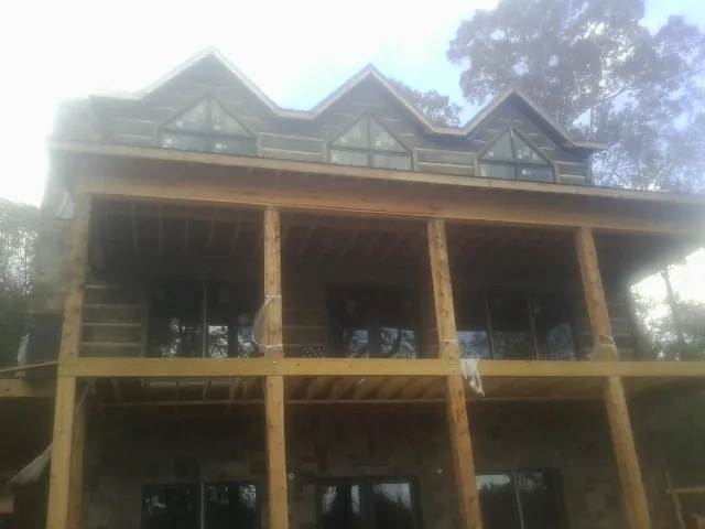 Dormers and porch framing on a large log home under construction — Roof Coating work by our crew in Southmont