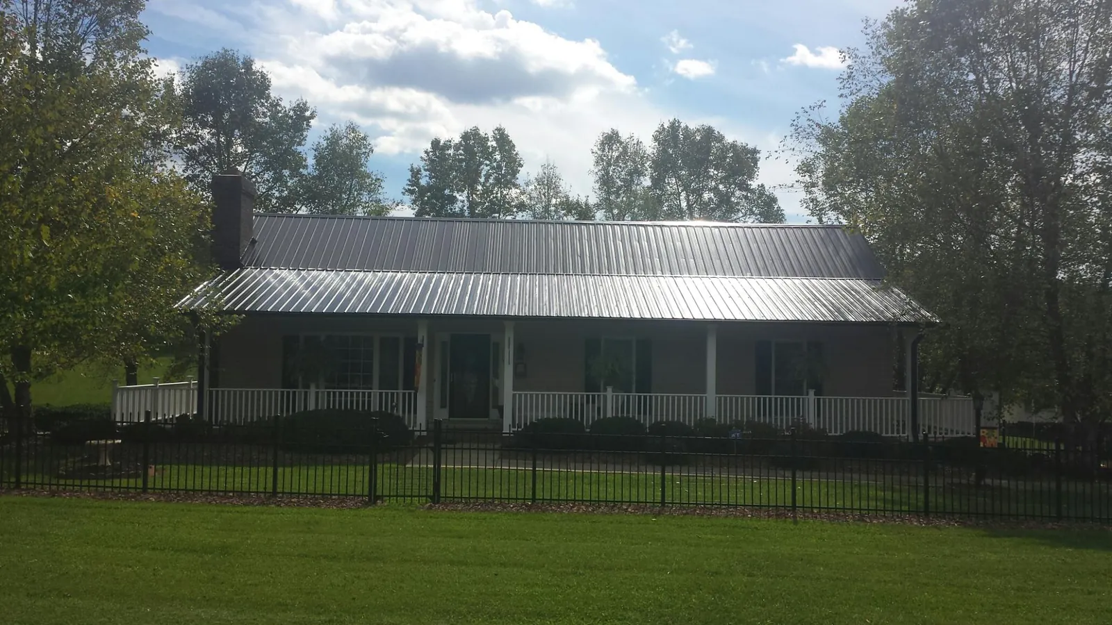 Gray metal roof on a brick ranch with a full width front porch — Gutter Guard Installation work by our crew in Southmont