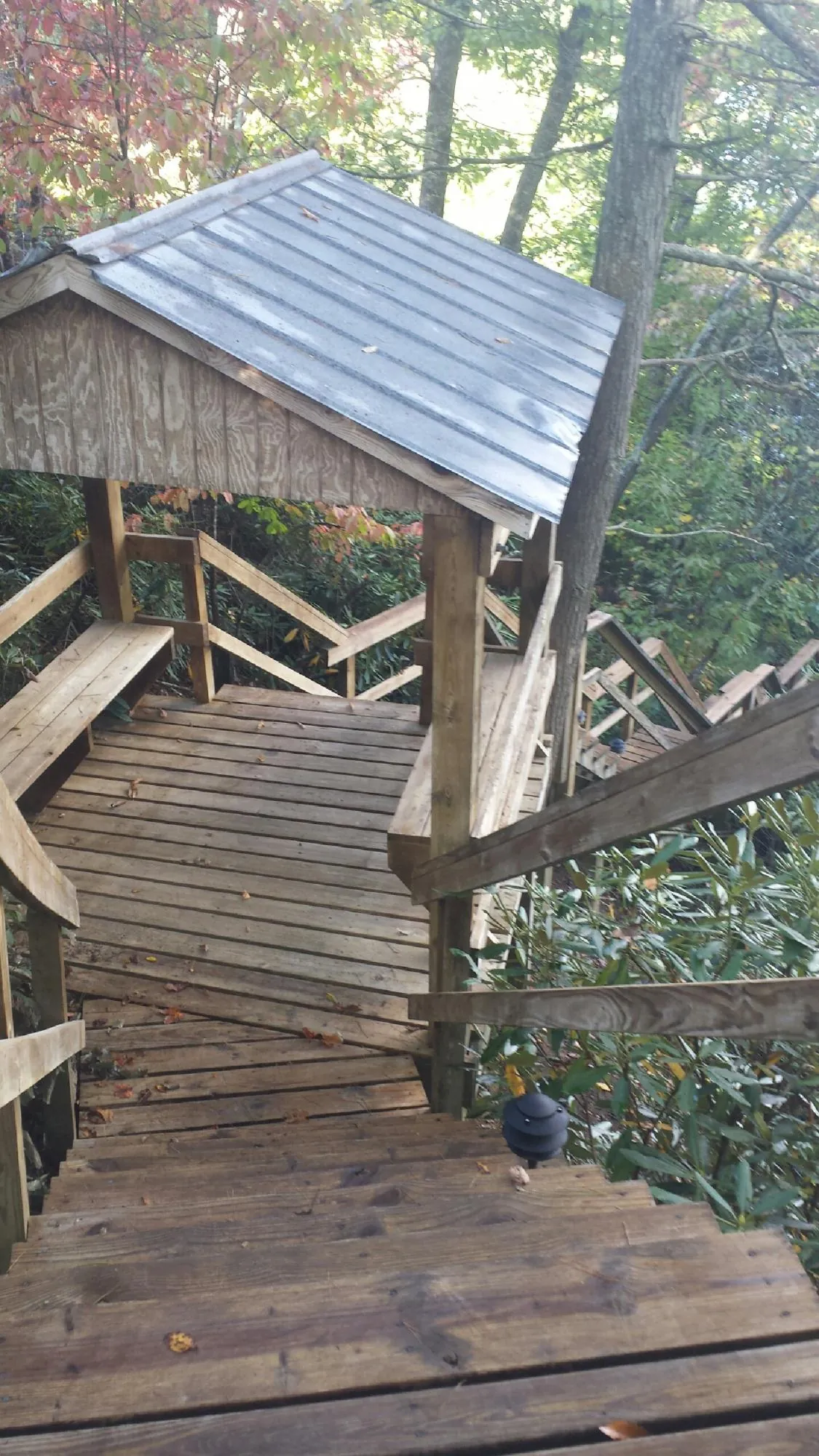 Metal roofed shelter over wooden steps on a wooded walkway — Skylight Repair & Installation work by our crew in Southmont