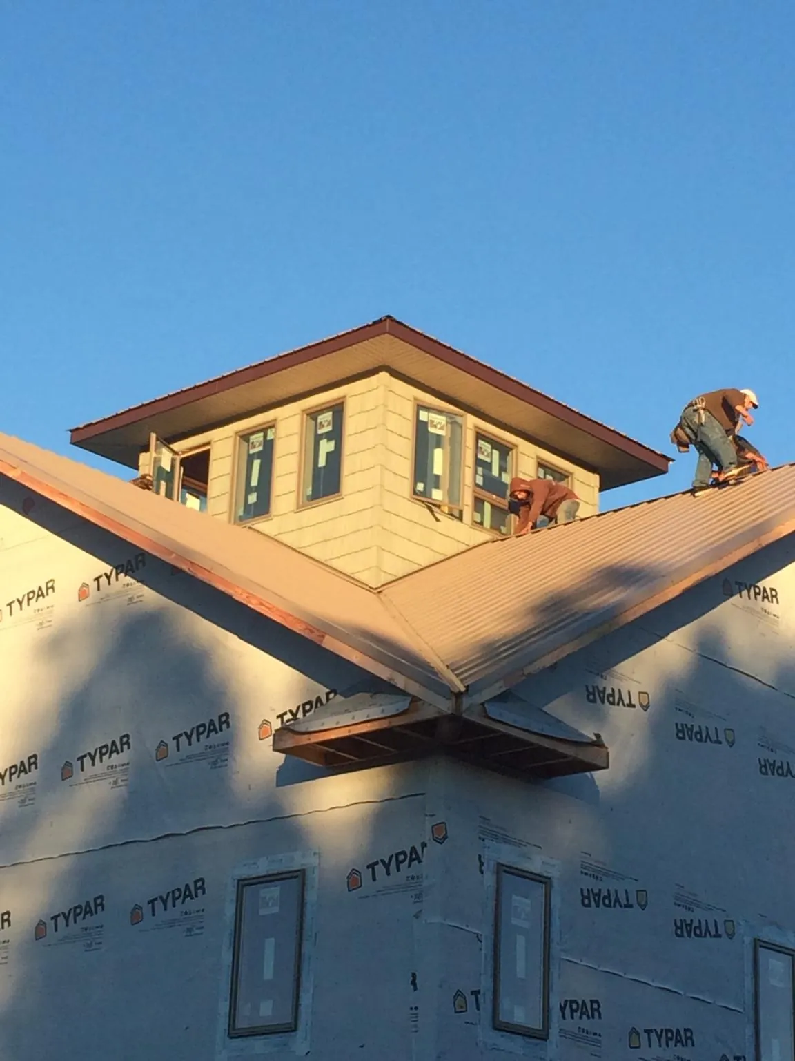 Roofers working around a rooftop cupola on a new metal roof at sunset — Roof Waterproofing in Southmont by Roofing Brothers